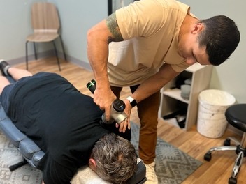 Percussion massage on a patient's upper back at Full Swing Healthcare in Jacksonville, FL